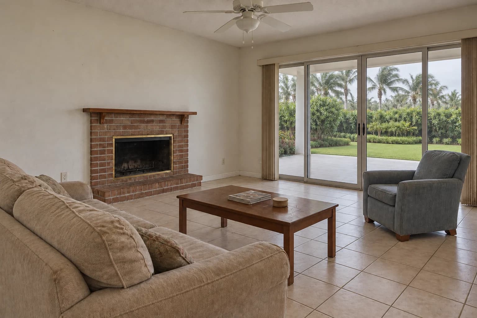 The Oak House — Before concept: an ordinary Naples living room with a basic brick fireplace, worn tile, faded furniture, simple blinds, and soft overcast daylight